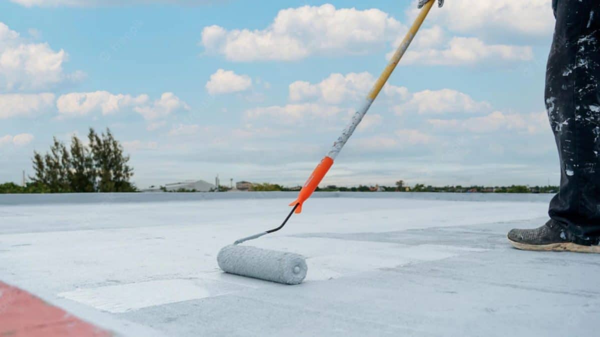 White reflective roof coating being applied on a building