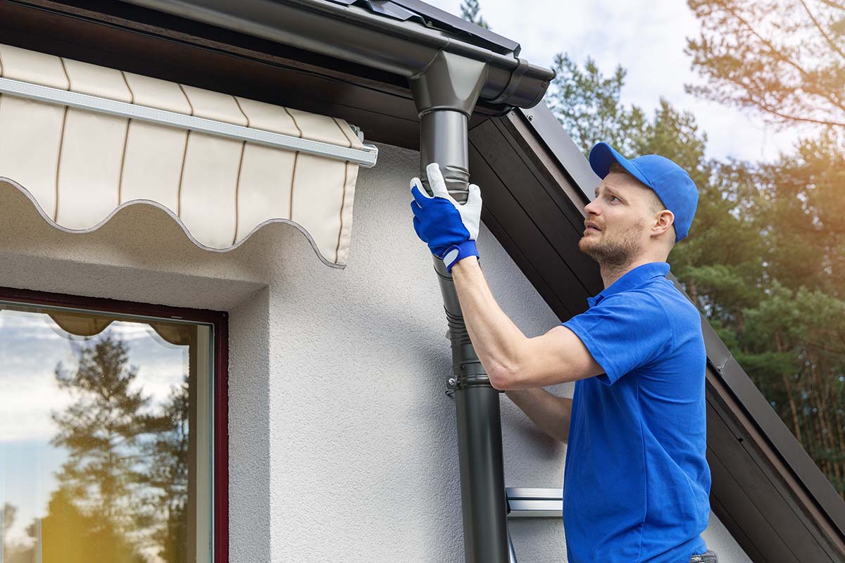 Technician repairing and cleaning a residential gutter
